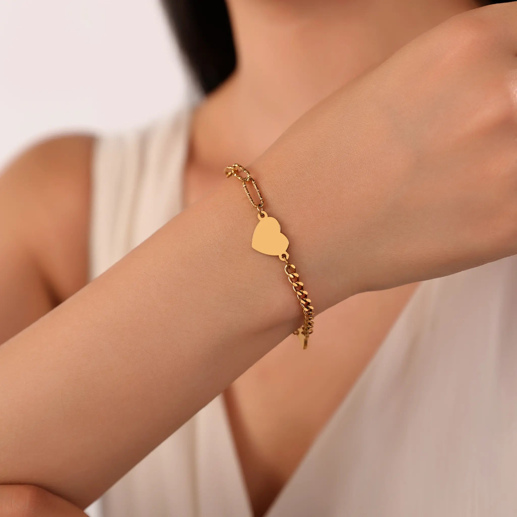 Woman wearing Vilrian gold asymmetric heart charm chain bracelet on wrist