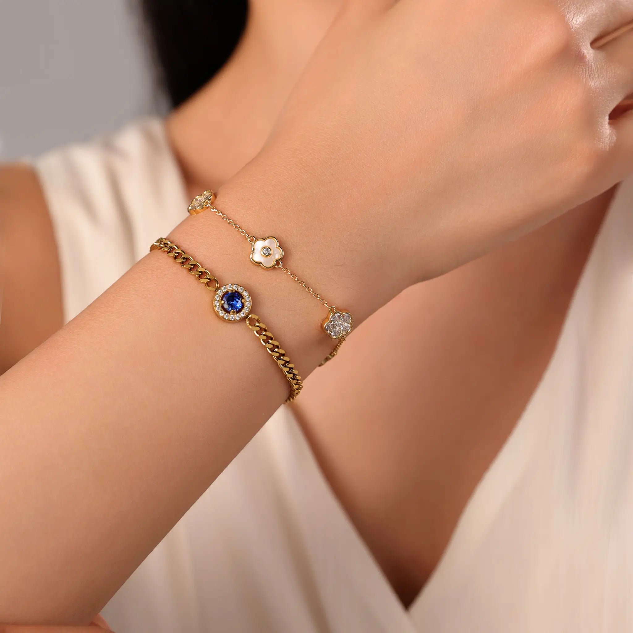 Layered gold bracelet styling with Vilrian sapphire blue curb bracelet and white shell flower bracelet