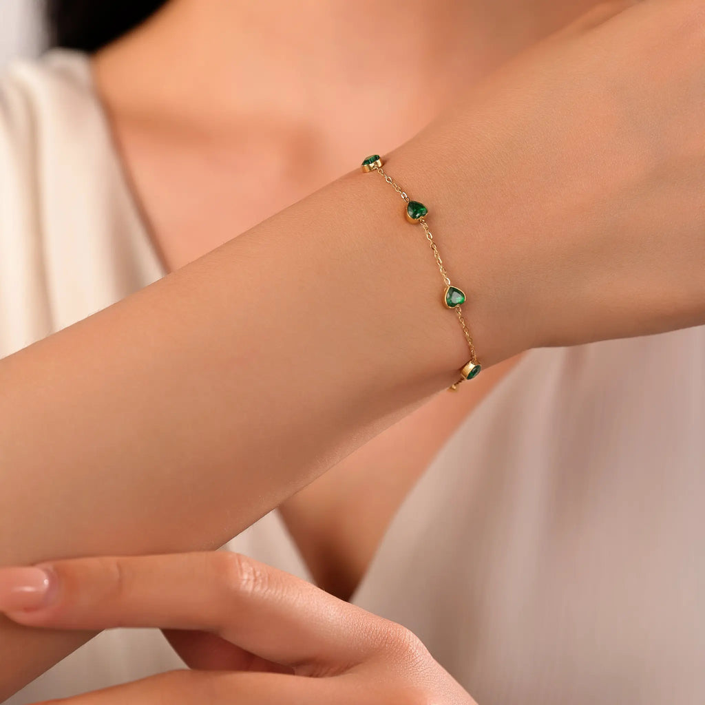 Woman wearing delicate Vilrian gold chain bracelet with emerald green heart zirconia on wrist