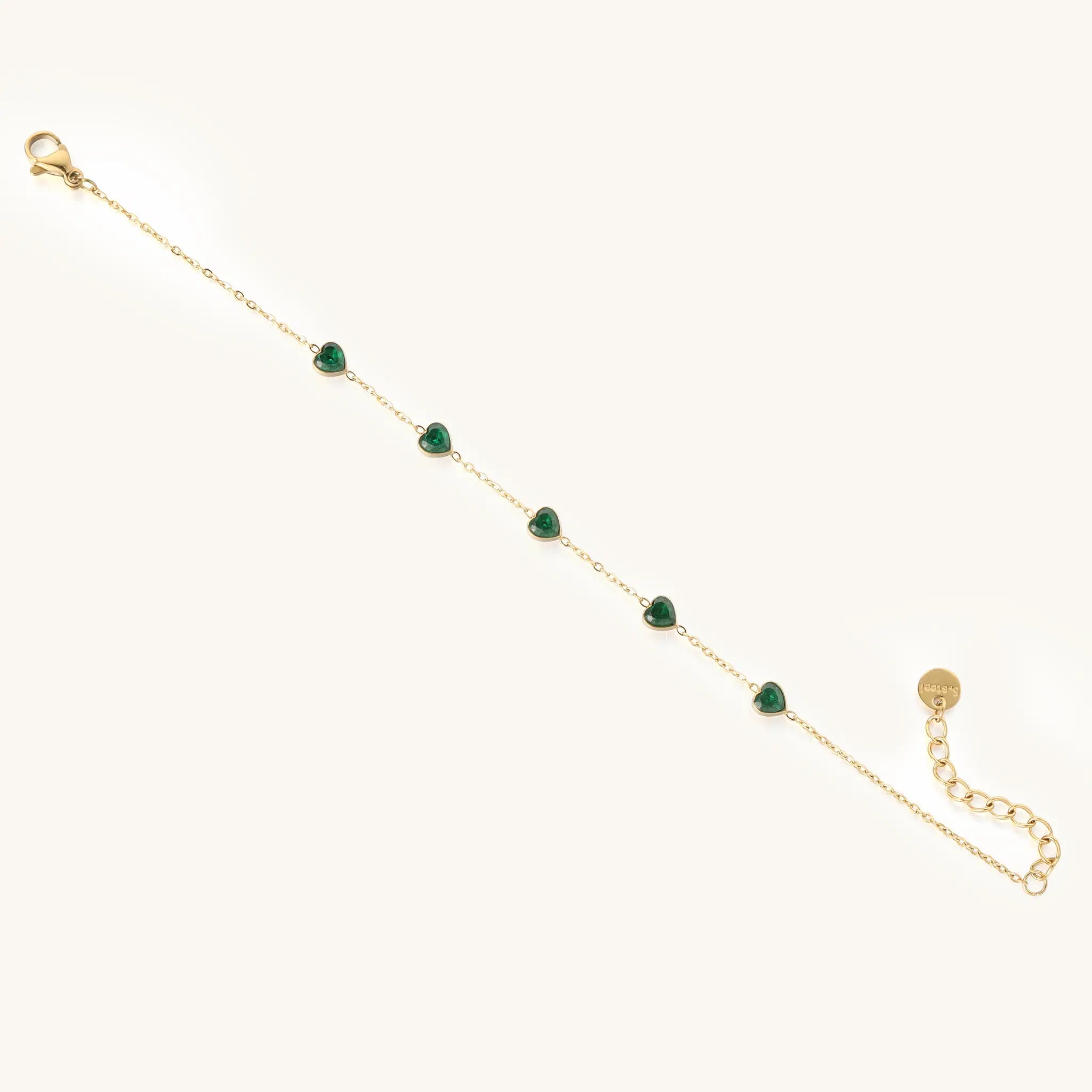 Full length flat lay of Vilrian gold chain bracelet with emerald green heart zirconia gems