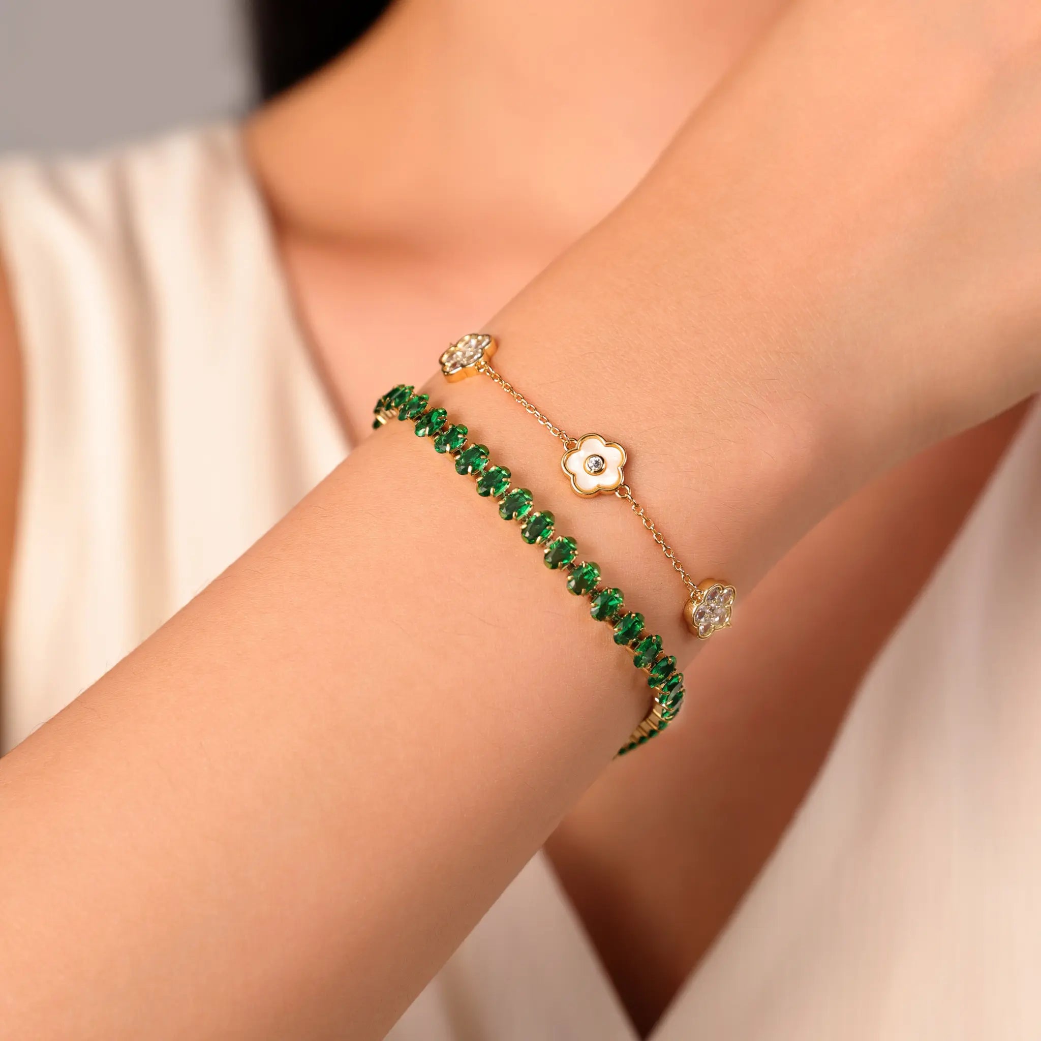 Gold bracelet stacking style featuring Vilrian floral charm bracelet and green gemstone chain