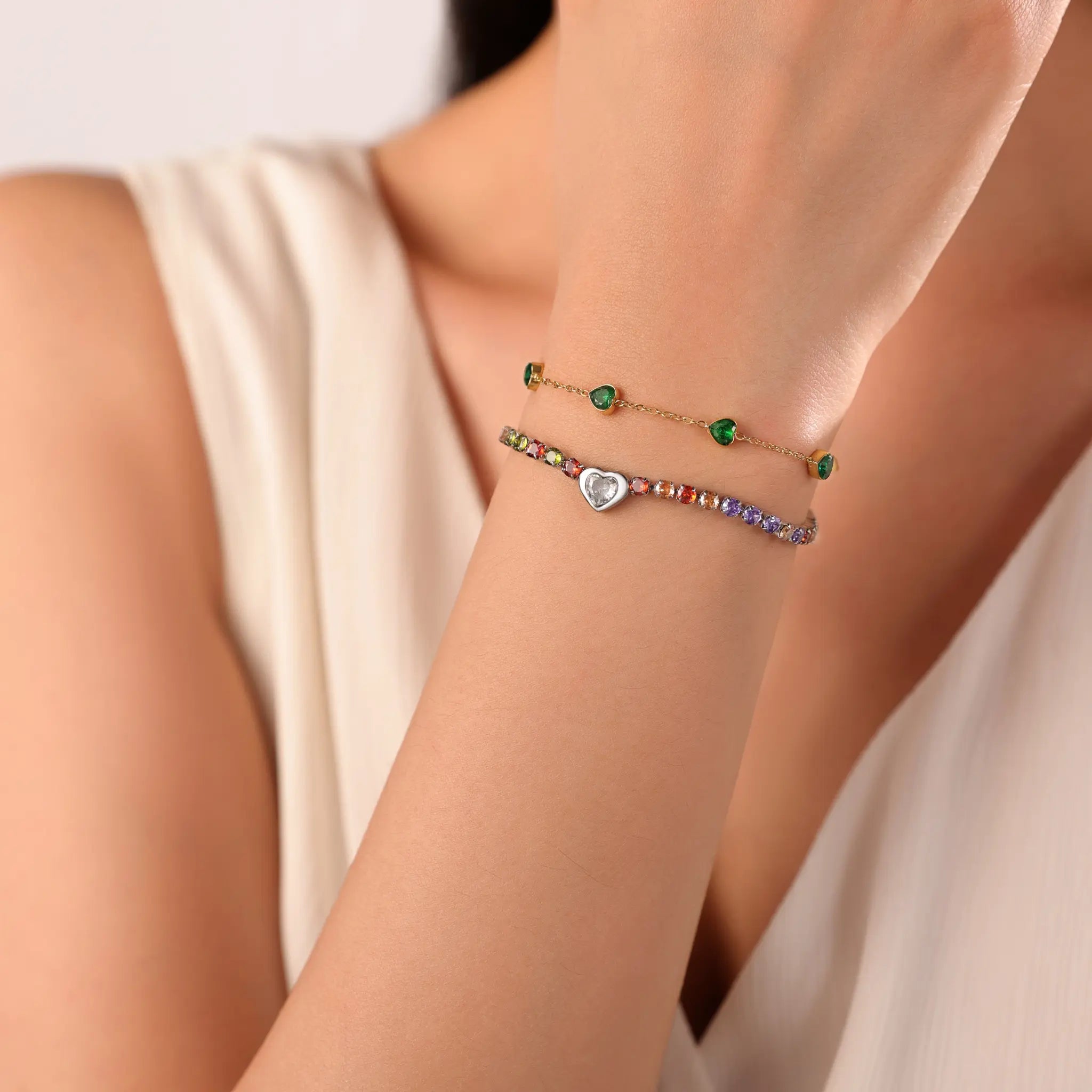 Gold bracelet stacking look featuring Vilrian green heart station bracelet and rainbow tennis bracelet