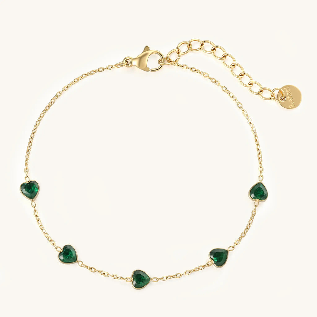 Top view of Vilrian gold green heart zirconia bracelet with logo disc and extension chain