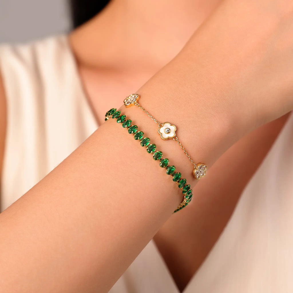 Gold bracelet stacking style featuring Vilrian green tennis bracelet and floral charm bracelet