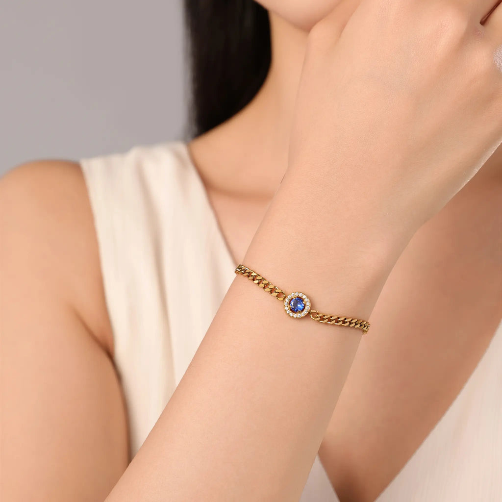 Woman wearing Vilrian gold curb chain bracelet with royal blue halo zirconia on wrist